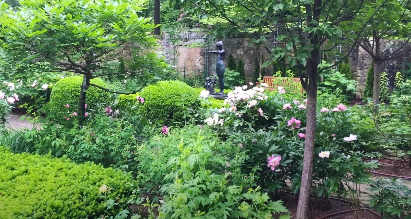 Lush garden with fountain statue and flowering plants in Stanton, CA