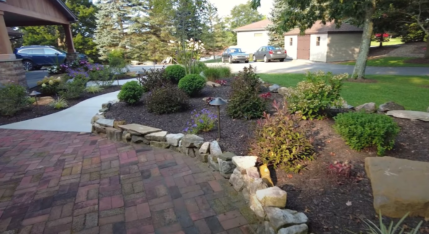 Stone retaining wall with paver driveway and ornamental grasses in Stanton, CA